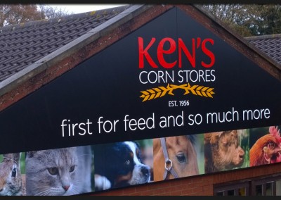 Triangular composite panels with vinyl print graphics and shape cut acrylic lettering and logo for Kens Corn Stores building gable end sign