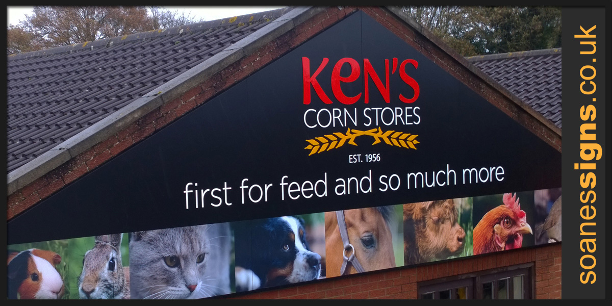 Triangular composite panels with vinyl print graphics and shape cut acrylic lettering and logo for Kens Corn Stores building gable end sign