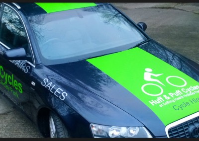 Vehicle wrap vinyl applied as green full racing stripe to bonnet roof and boot of Huff and Puff Cycles Audi A6 along with branding vinyl graphic