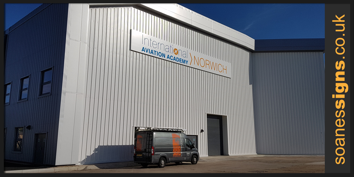 Six sections hangar sign fabricated from white folded pans with aluminium rail support and vinyl graphics applied, installed for International Aviation Academy Norwich
